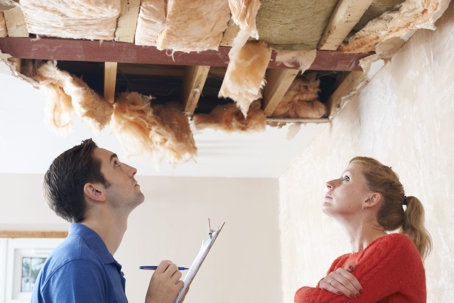 homeowner and worker looking up at roof damage