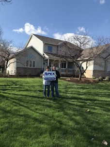 Homeowners holding APEX lawn sign