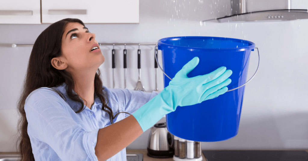 A woman containing a roof leak with a bucket.